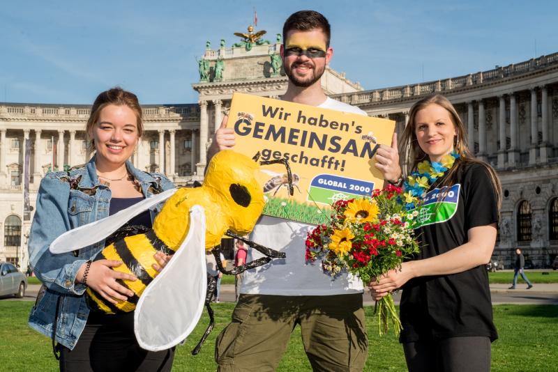 Aktivist:innen mit Biene und Schild vor Nationalbibliothek