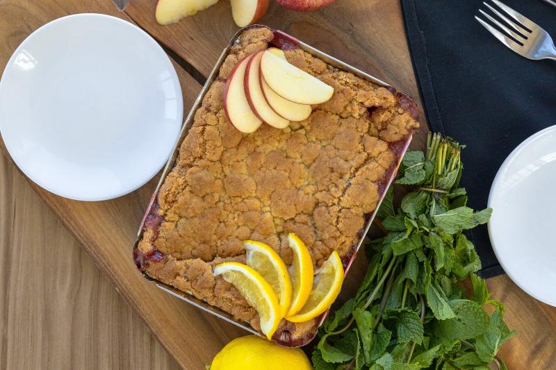 Apfel-Crumble serviert mit Apfel-Stücken und Zitrone