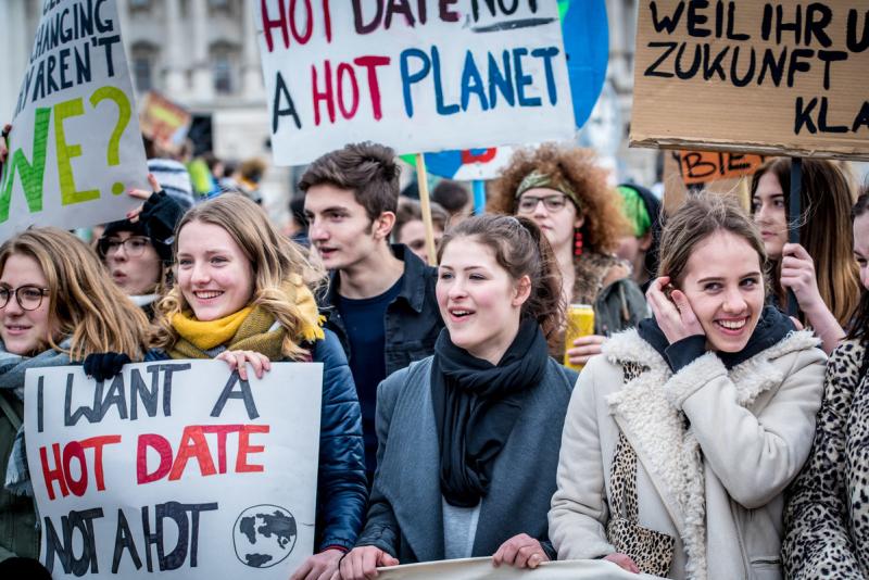 Junge Menschen bei einem Klimastreik mit Plakaten und Banner