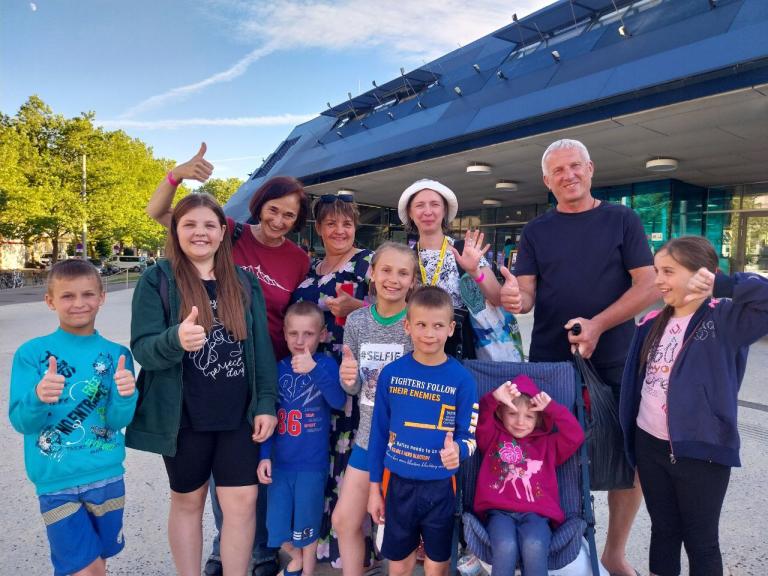 Kinder und Erwachsene stehen für ein Gruppenfoto zusammen und lachen in die Kamera