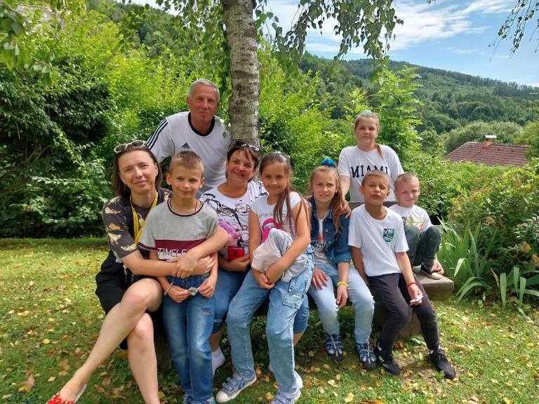 Kinder und Erwachsene sitzen für ein Gruppenfoto unter einem Baum zusammen