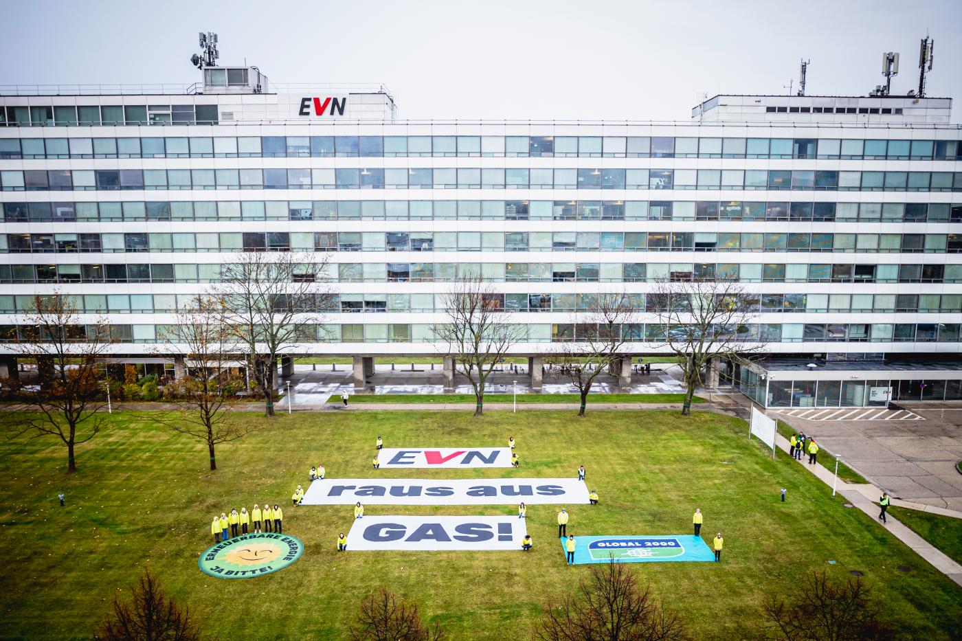 Banner mit der Aufschrift "EVN – Raus aus Gas!" liegt auf einer Wiese vor dem EVN-Hauptgebäude