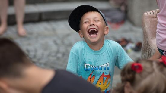 Junge spielt mit Wasser bei einem Brunnen und lacht