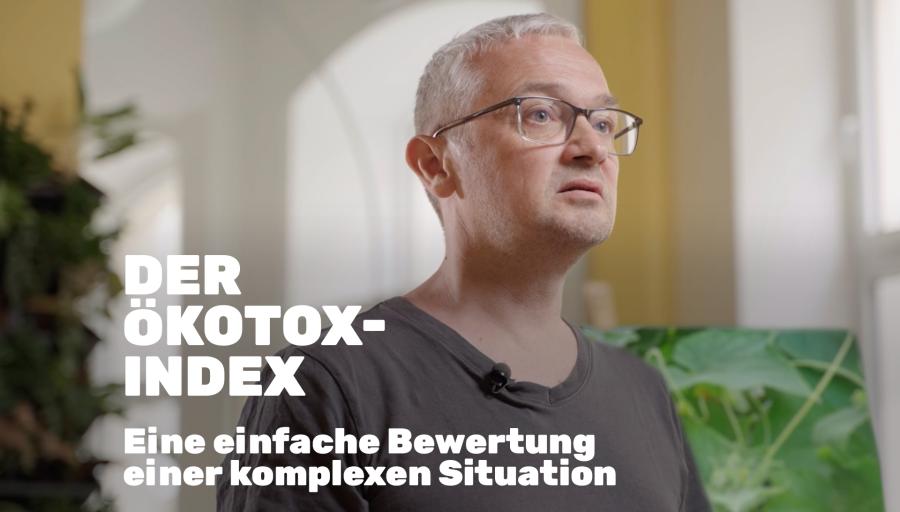 Ein Close-Up von einem Mann mit grauen Haaren und Brille steht aufrecht in einem Raum und schaut in die Ferne. "Der Ökotox-Index - Eine einfache Bewertung einer komplexen Situation" steht links in der Ecke