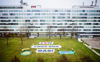 Banner mit der Aufschrift "EVN – Raus aus Gas!" liegt auf einer Wiese vor dem EVN-Hauptgebäude