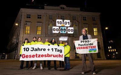 Aktivist:innen stehen vor dem Bundesministerium und halten einen Banner in der Hand: "10 Jahre + 1 Tag Gesetzesbruch"